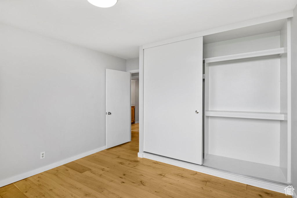 Unfurnished bedroom with baseboards, a closet, and wood finished floors