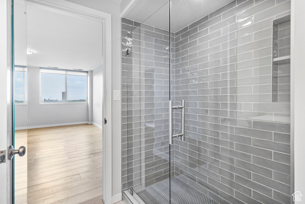 Bathroom with baseboards, a shower stall, and wood finished floors