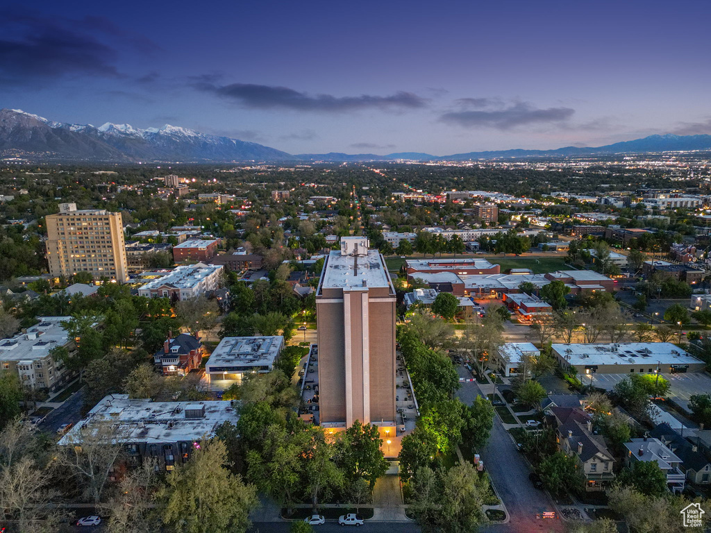 Aerial view of property and surrounding area featuring mountains and nearby urban area