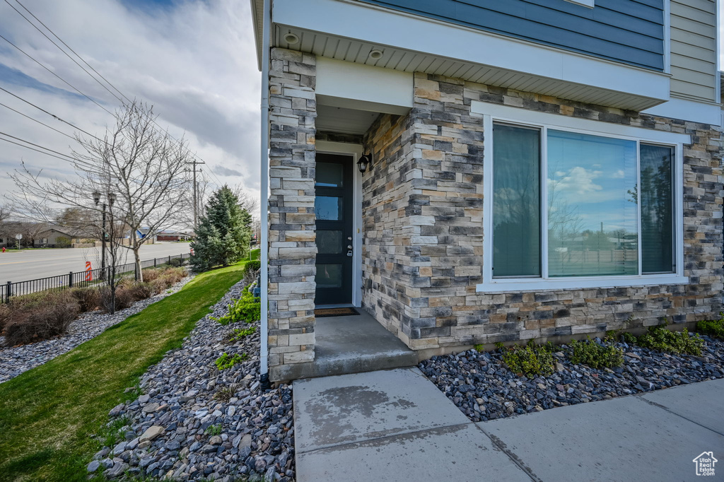 Entrance to property featuring stone siding and fence