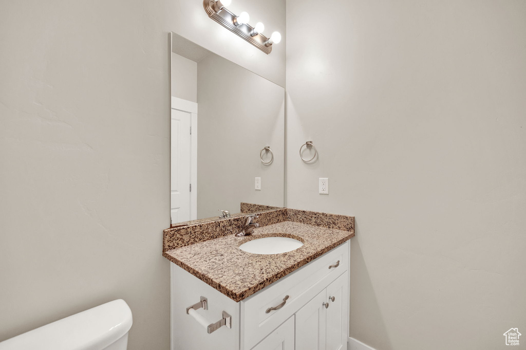 Half bathroom featuring vanity and toilet