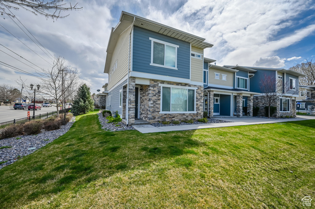 Rear view of house with stone siding, a yard, and fence