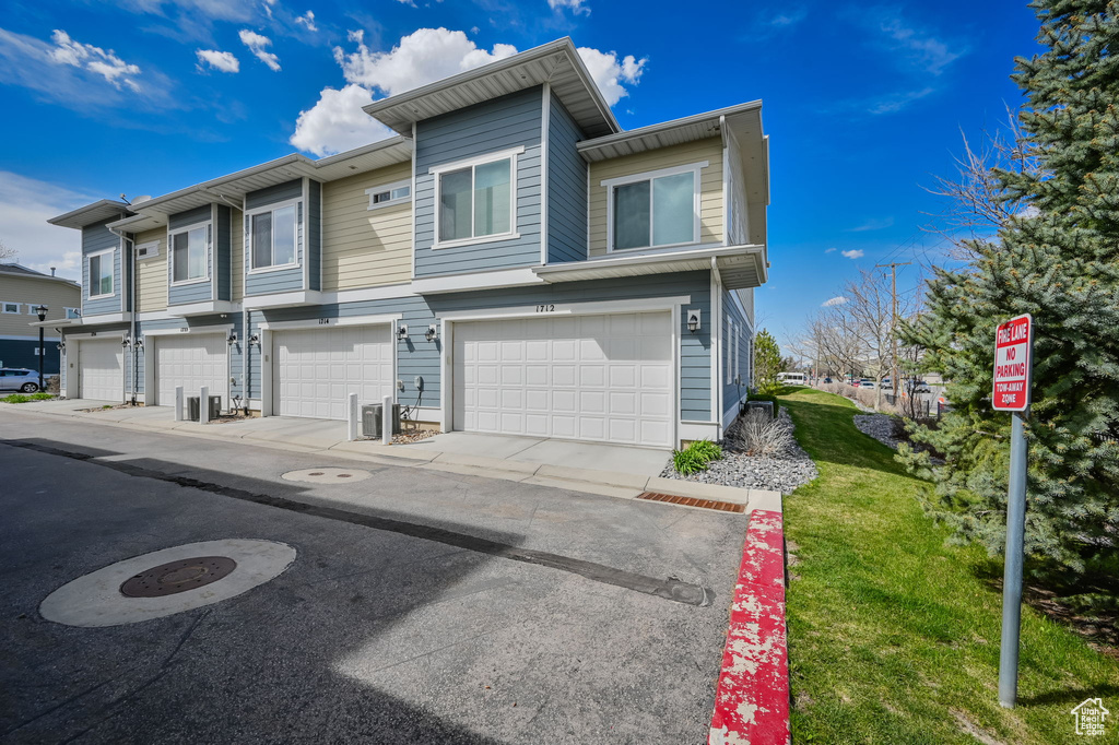 Multi unit property featuring an attached garage and a front yard