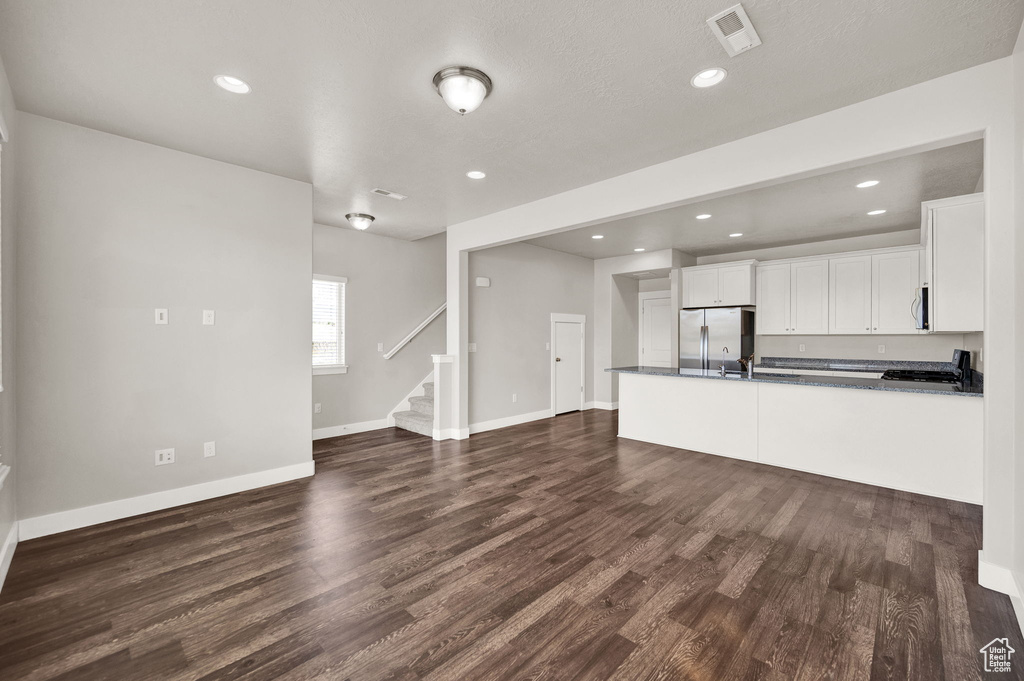 Unfurnished living room with stairs, visible vents, recessed lighting, dark wood finished floors, and baseboards