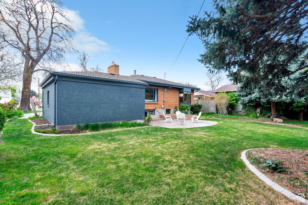 Back of house with fence, a patio, a chimney, and a lawn