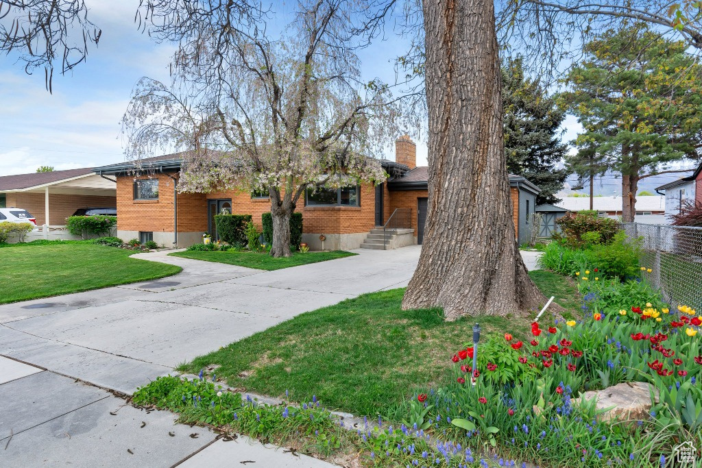View of front of home with a chimney, a front yard, driveway, and fence