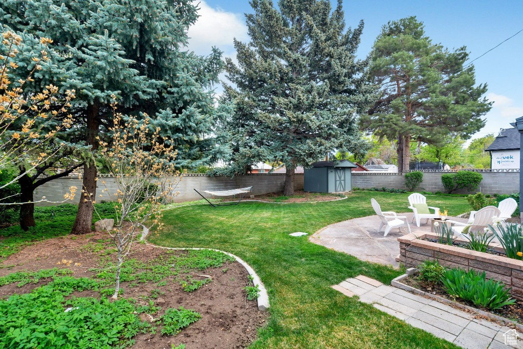 View of yard with an outdoor structure, a shed, a fenced backyard, and a patio