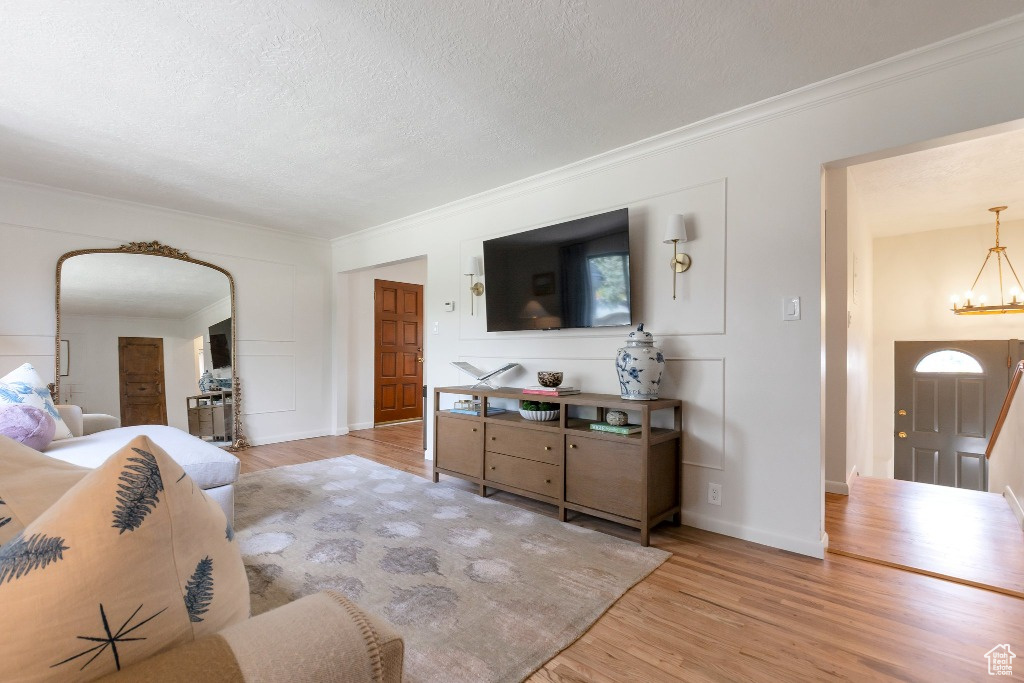 Living room with crown molding, arched walkways, an inviting chandelier, and wood finished floors