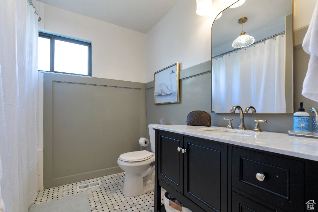 Bathroom featuring curtained shower, vanity, toilet, and visible vents