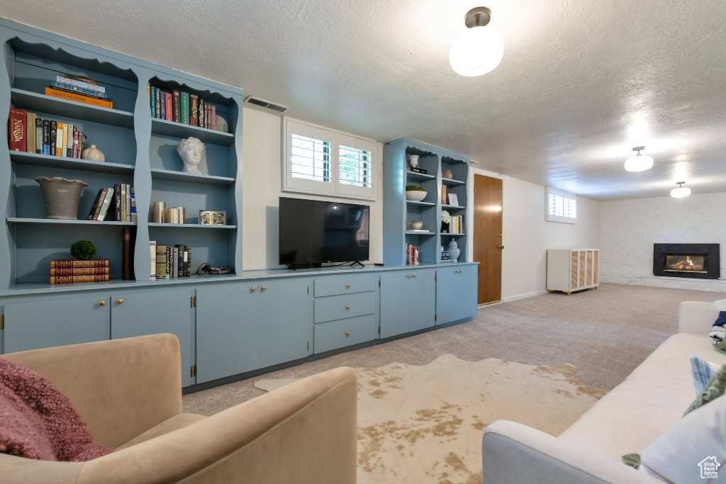 Living room with light carpet, a fireplace, visible vents, and a textured ceiling