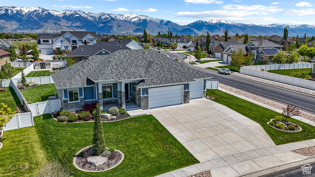 View of front of house with an attached garage, a gate, a residential view, a fenced backyard, and driveway