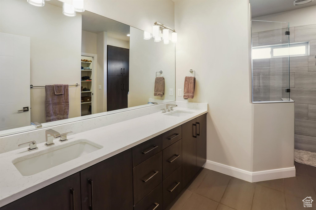 Bathroom featuring a sink, a tile shower, double vanity, and tile patterned floors