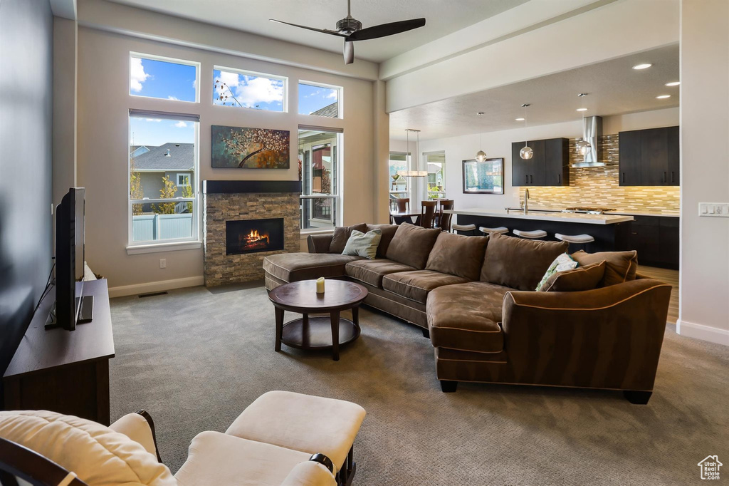 Carpeted living room featuring a wealth of natural light, baseboards, and a ceiling fan