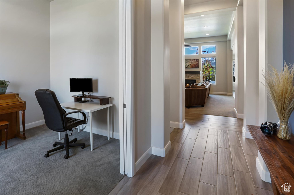 Office area featuring a fireplace, baseboards, and wood finished floors