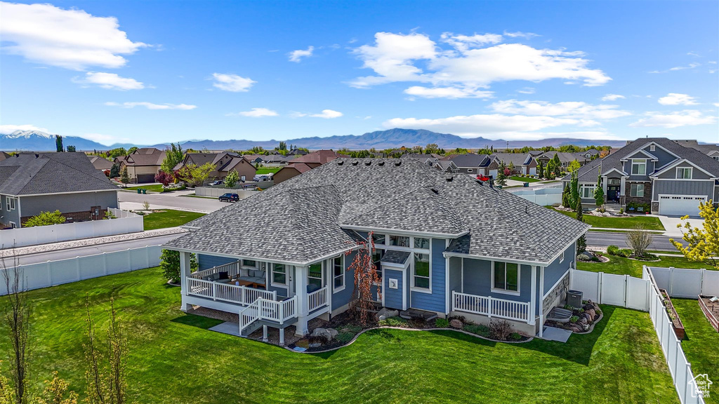 Rear view of property with a yard, a mountain view, a residential view, a shingled roof, and a fenced backyard