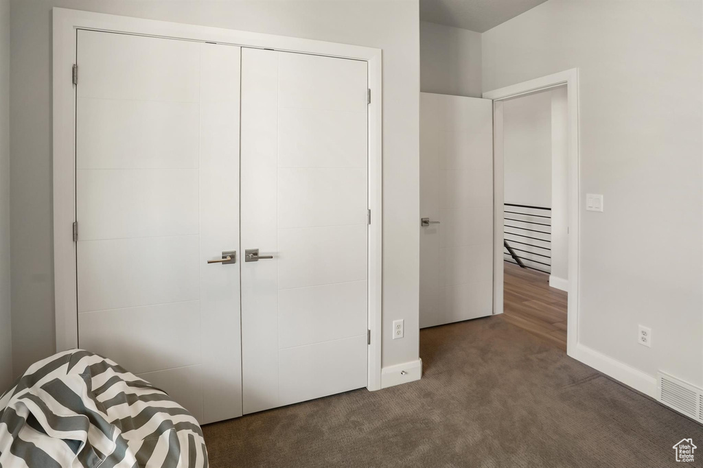 Bedroom featuring baseboards, dark carpet, a closet, and visible vents
