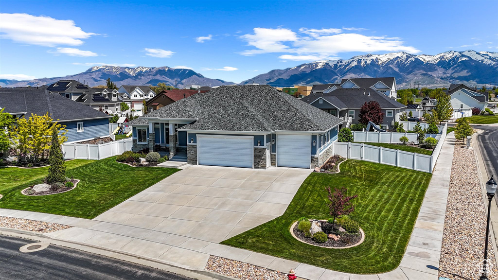 Ranch-style house with an attached garage, a mountain view, a residential view, a front lawn, and driveway