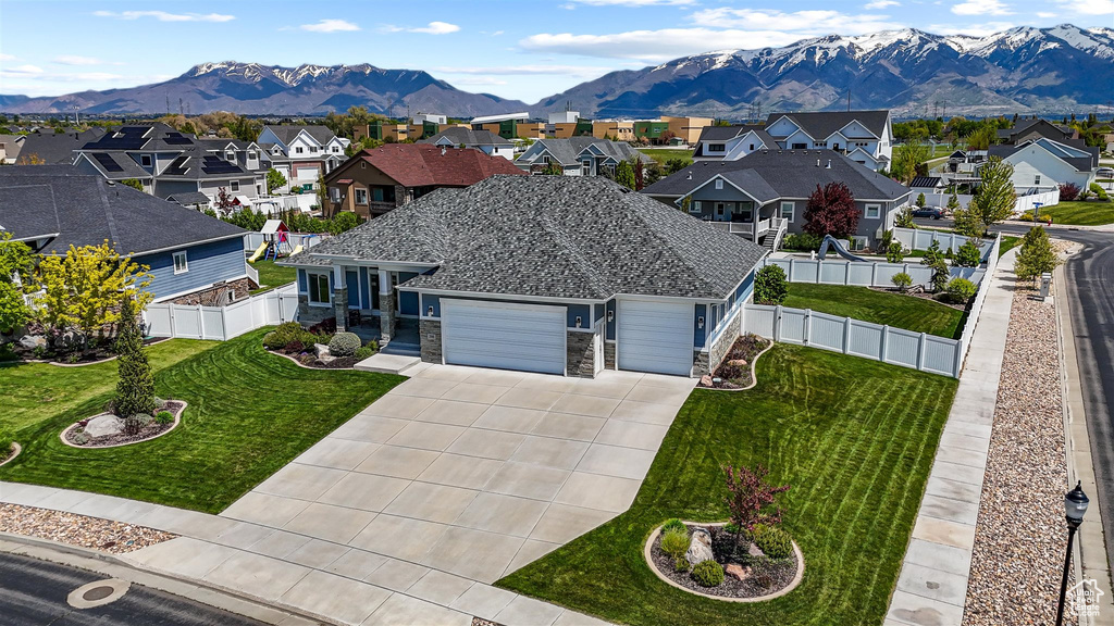 View of front of home featuring an attached garage, a mountain view, a residential view, a front yard, and driveway