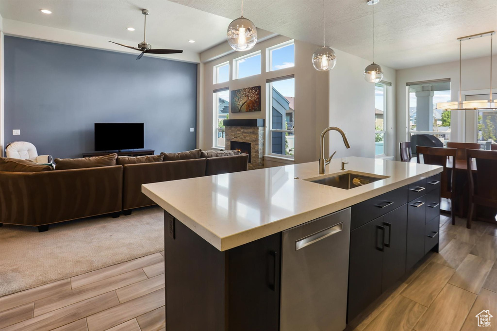 Kitchen featuring a sink, a center island with sink, open floor plan, light countertops, and a ceiling fan