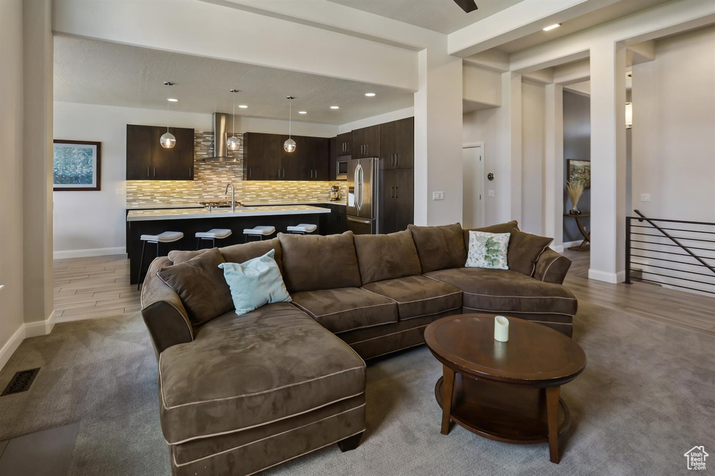Carpeted living room featuring a sink, baseboards, visible vents, and recessed lighting