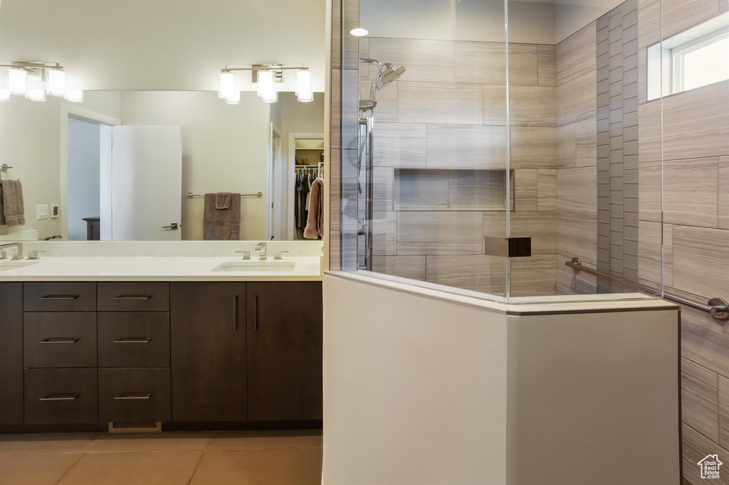 Full bathroom featuring walk in shower, a sink, tile patterned flooring, a walk in closet, and double vanity