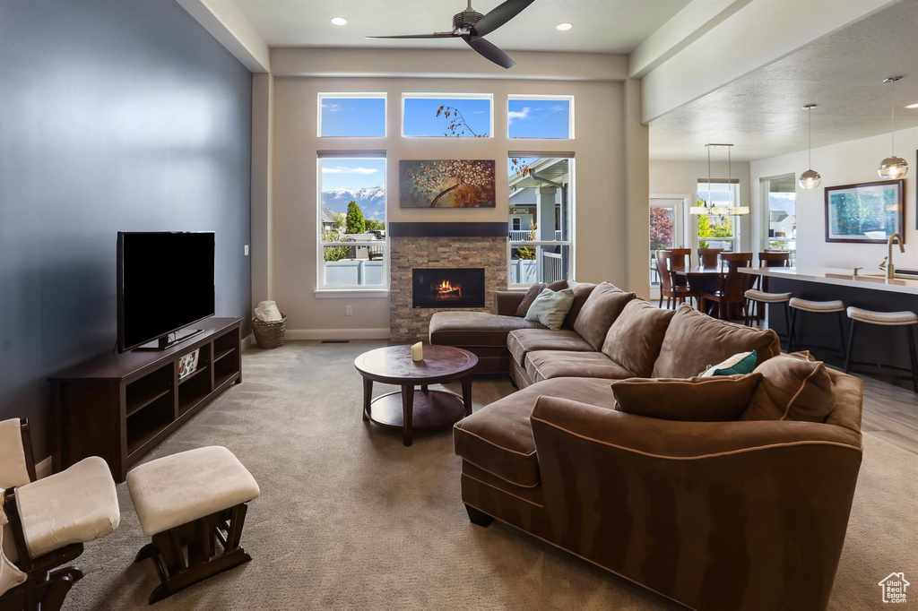 Living room with a wealth of natural light, a fireplace, ceiling fan, and carpet floors