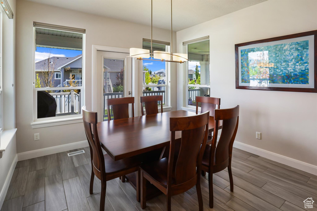 Dining space with baseboards, a notable chandelier, visible vents, and wood finished floors