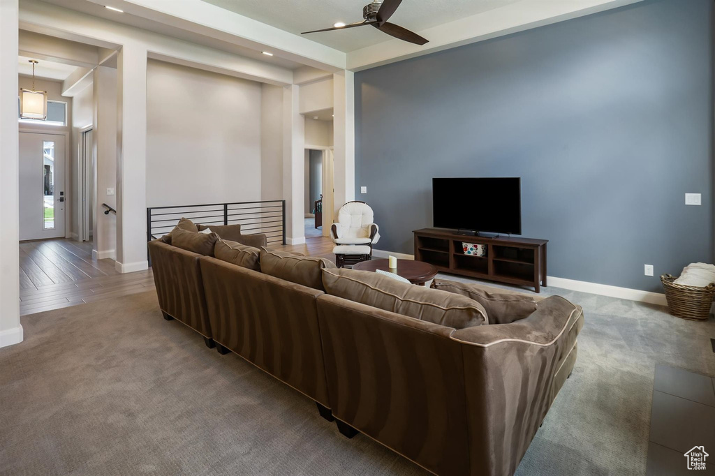 Living area featuring carpet, baseboards, ceiling fan, and recessed lighting