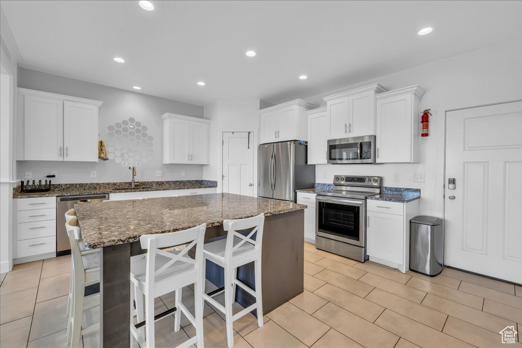 Kitchen with a sink, recessed lighting, a center island, white cabinets, and appliances with stainless steel finishes