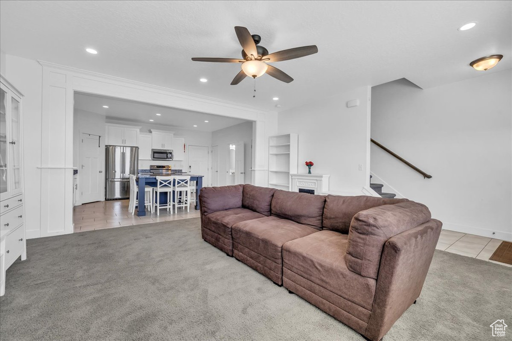 Living room with light tile patterned floors, a ceiling fan, stairway, light carpet, and recessed lighting