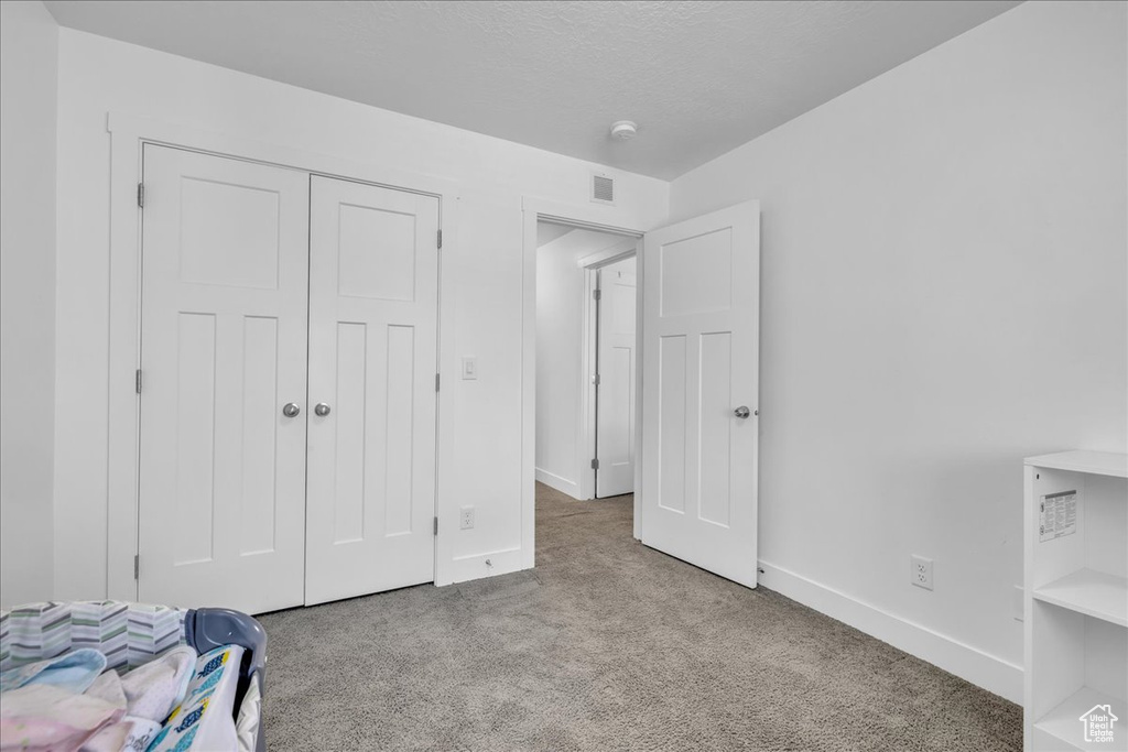 Unfurnished bedroom with baseboards, a closet, visible vents, and carpet floors