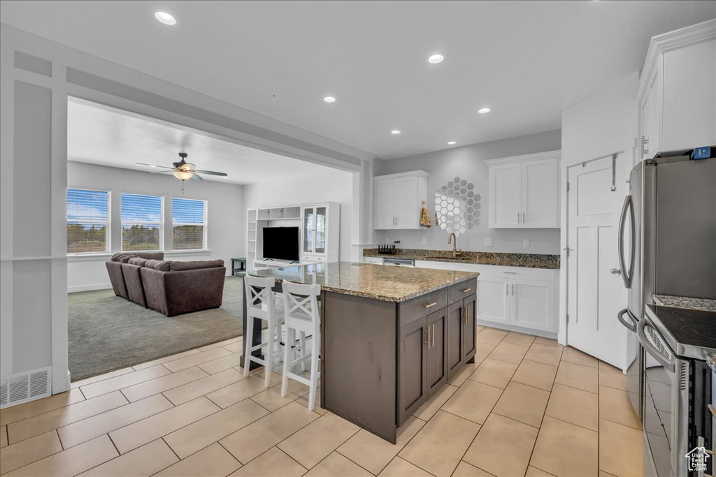 Kitchen featuring a kitchen island, white cabinets, a sink, and electric range