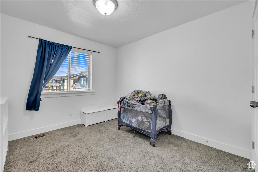 Carpeted bedroom with a textured ceiling, visible vents, and baseboards