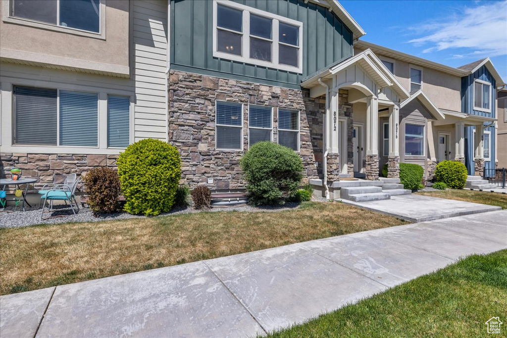View of front of property featuring stone siding, a front yard, and board and batten siding