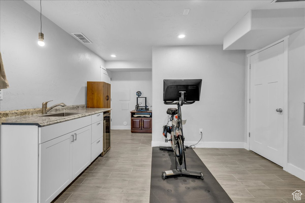 Exercise area featuring recessed lighting, light wood-style floors, visible vents, and a sink