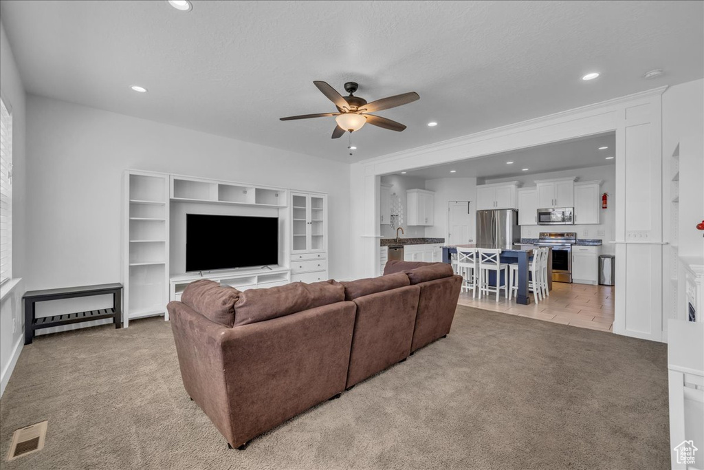 Living room with a ceiling fan, recessed lighting, baseboards, visible vents, and light carpet
