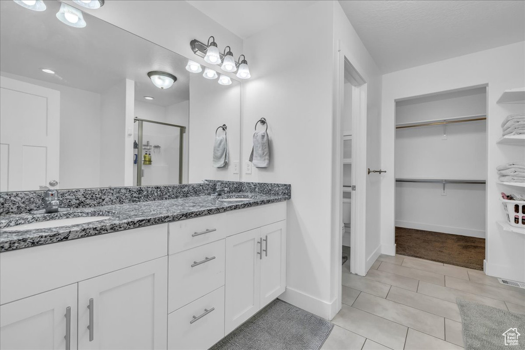 Bathroom with a sink, double vanity, a walk in closet, and a shower stall