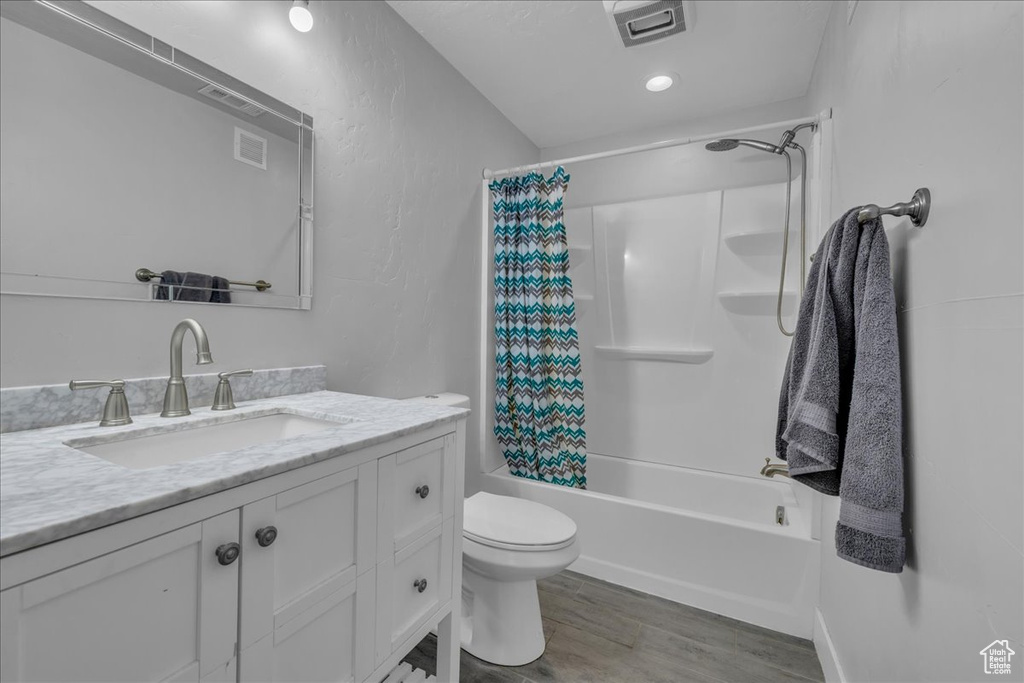 Full bathroom featuring toilet, wood finished floors, visible vents, shower / bathtub combination with curtain, and vanity