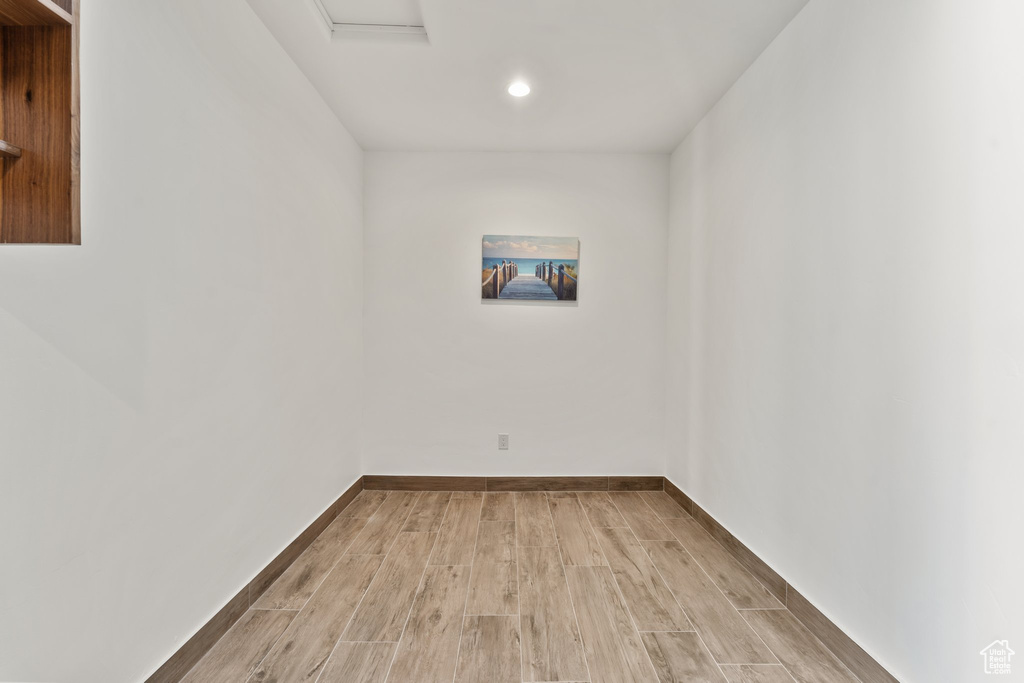 Empty room featuring attic access, baseboards, and wood finished floors