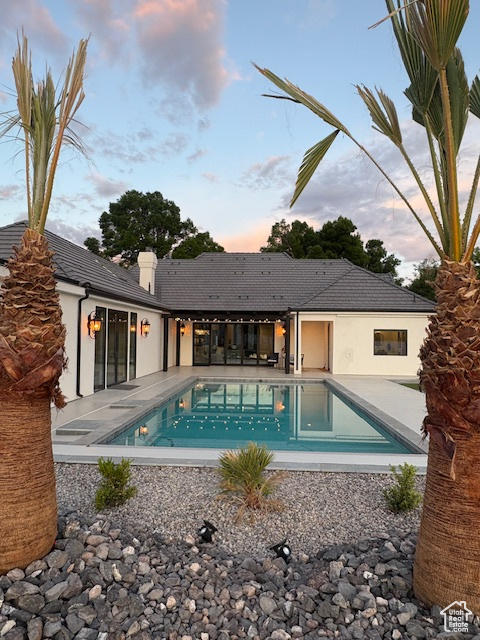 Pool at dusk with a patio area and an outdoor pool