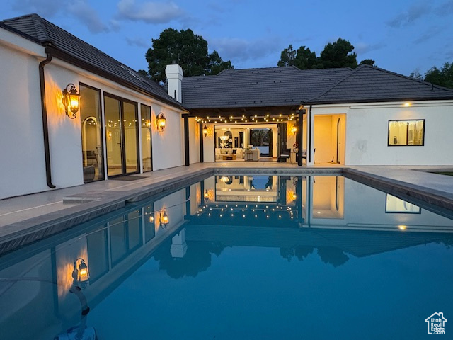 Back of house with a patio, a chimney, and an outdoor pool