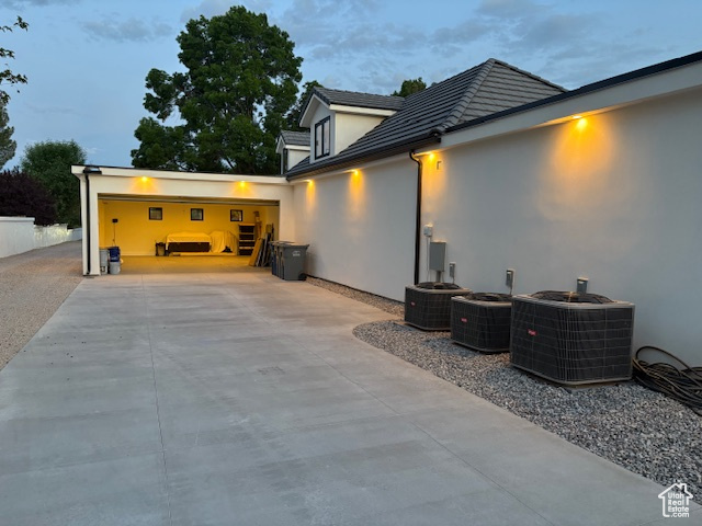 Exterior space with stucco siding, cooling unit, and driveway