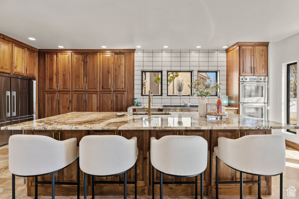 Kitchen with appliances with stainless steel finishes, a sink, light stone counters, and recessed lighting