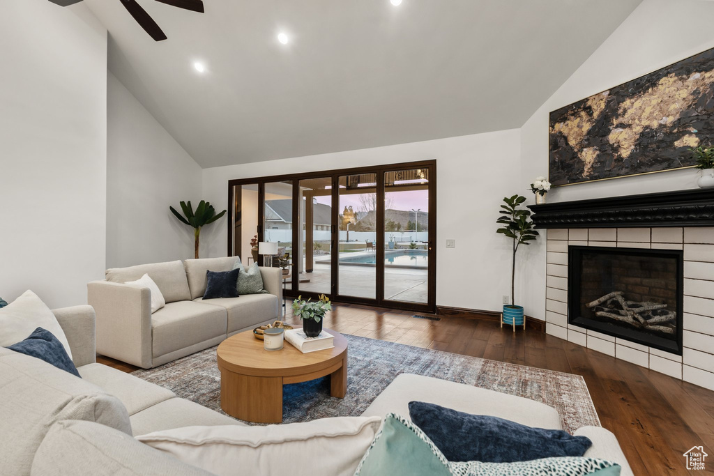 Living room featuring high vaulted ceiling, a fireplace, wood finished floors, a ceiling fan, and baseboards