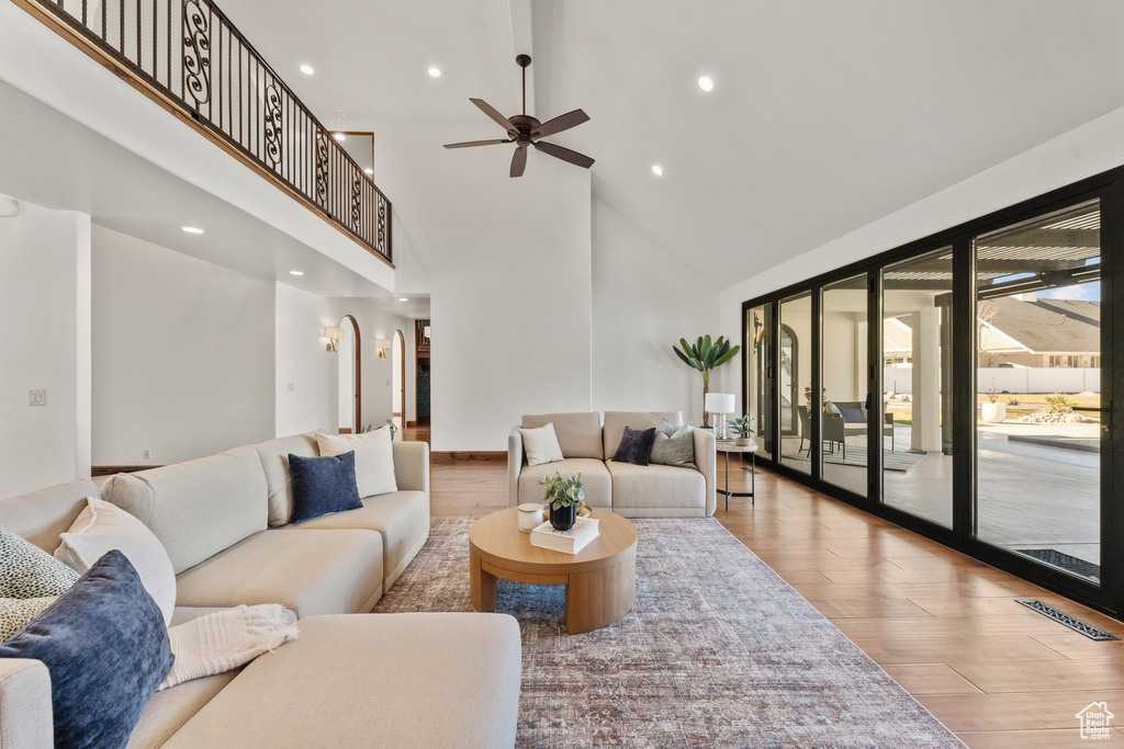 Living room featuring visible vents, ceiling fan, a high ceiling, and wood finished floors