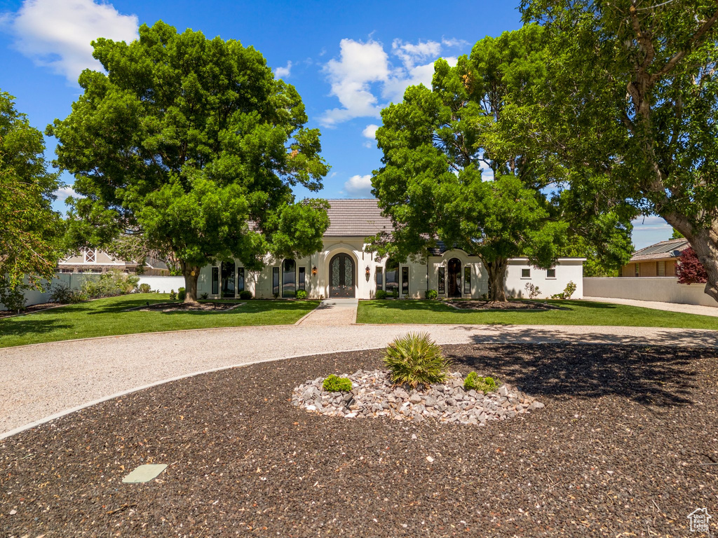 Obstructed view of property featuring a front yard, stucco siding, french doors, and a tile roof