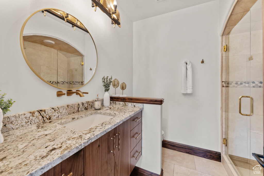 Full bathroom with toilet, a shower stall, vanity, tile patterned flooring, and baseboards