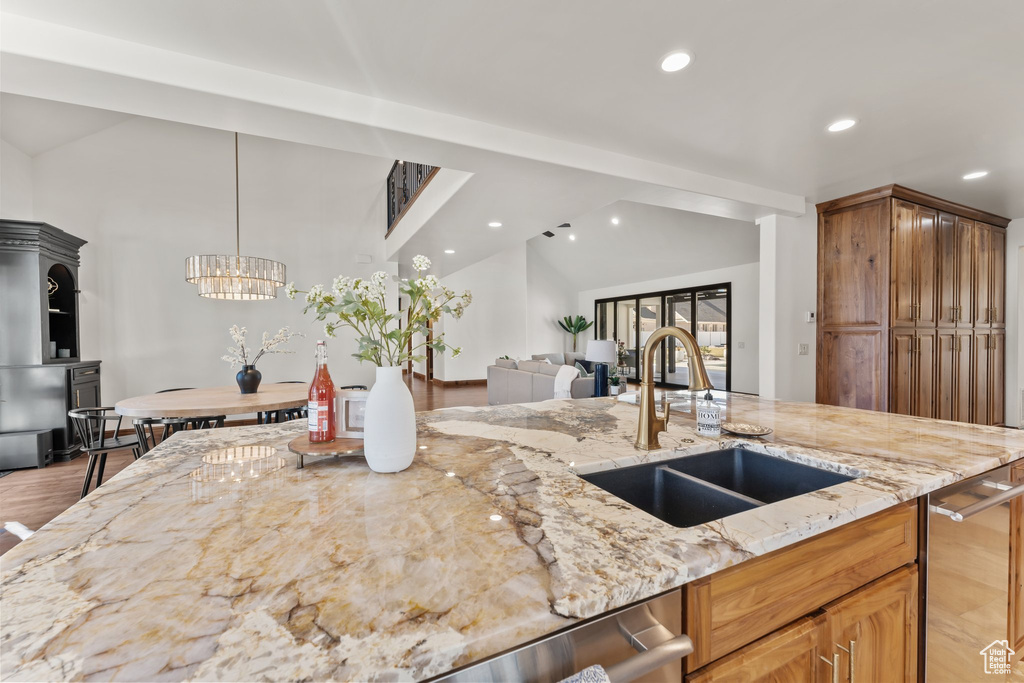 Kitchen with recessed lighting, open floor plan, vaulted ceiling, a sink, and light stone countertops