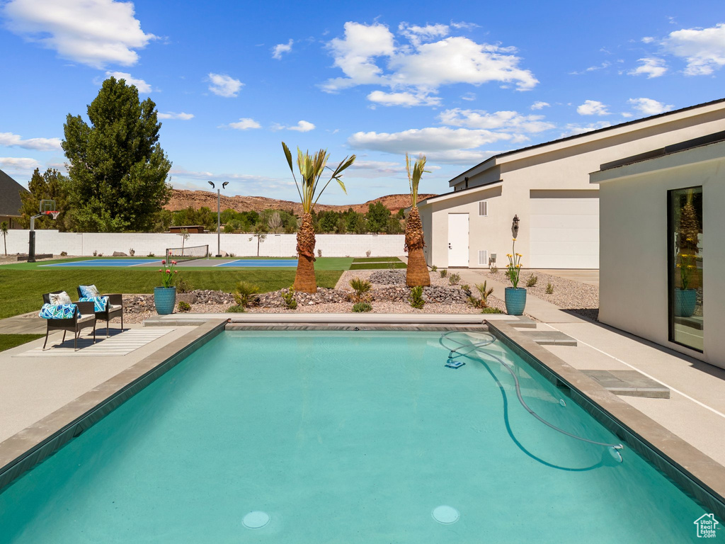 View of pool with a yard, a fenced in pool, a mountain view, fence, and a patio
