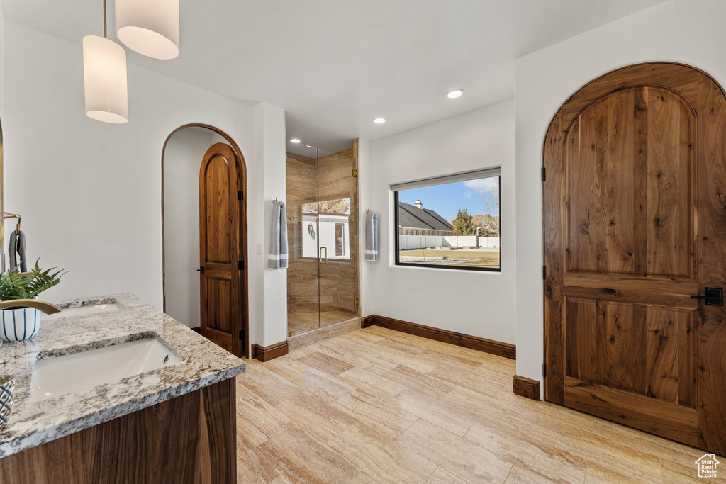 Bathroom featuring double vanity, baseboards, a shower stall, a sink, and recessed lighting